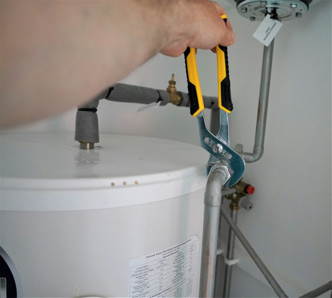 Technician tightening a pipe fitting on a water heater